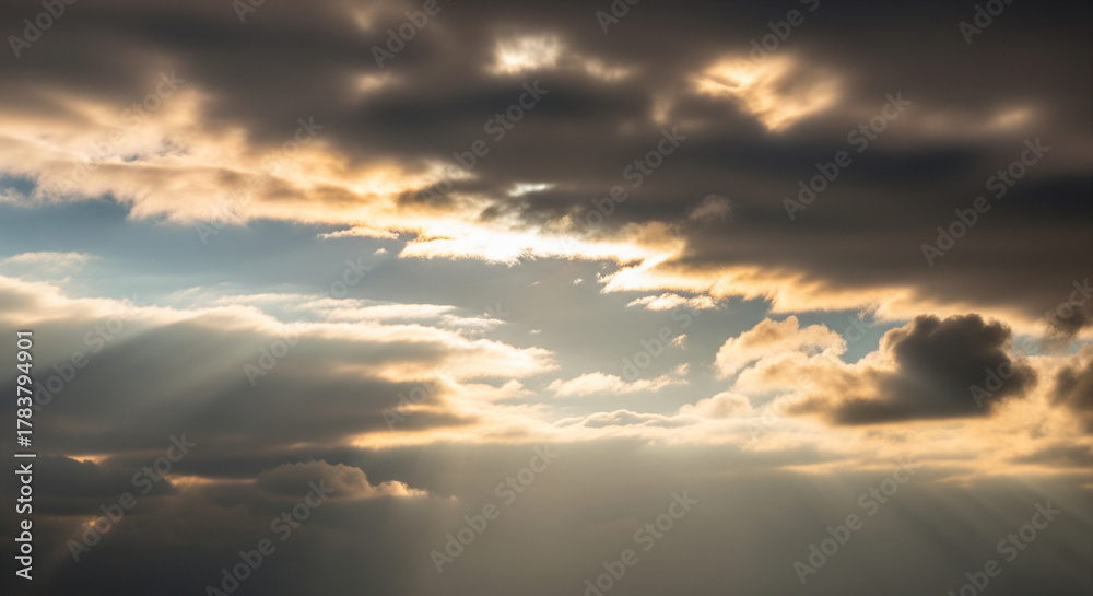 Obraz premium Golden sunbeams bursting through dramatic, dark storm clouds, symbolizing hope and divine light