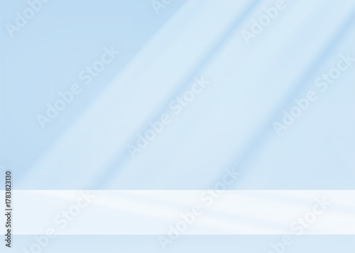 Empty studio background in soft blue tones with natural sunlight and window shadow patterns on wall. Minimalist limbo setup for product photography or presentation backdrop layouts.