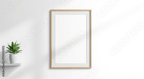 Clean and empty vertical wooden frame mockup with a green plant on a shelf, casting natural light shadows on a bright white wall, perfect for displaying art and design in a modern setting