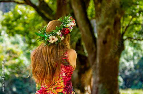 femme de dos aux cheveux long assisse en extérieur naturel avec une couronne de fleurs sur sa tête