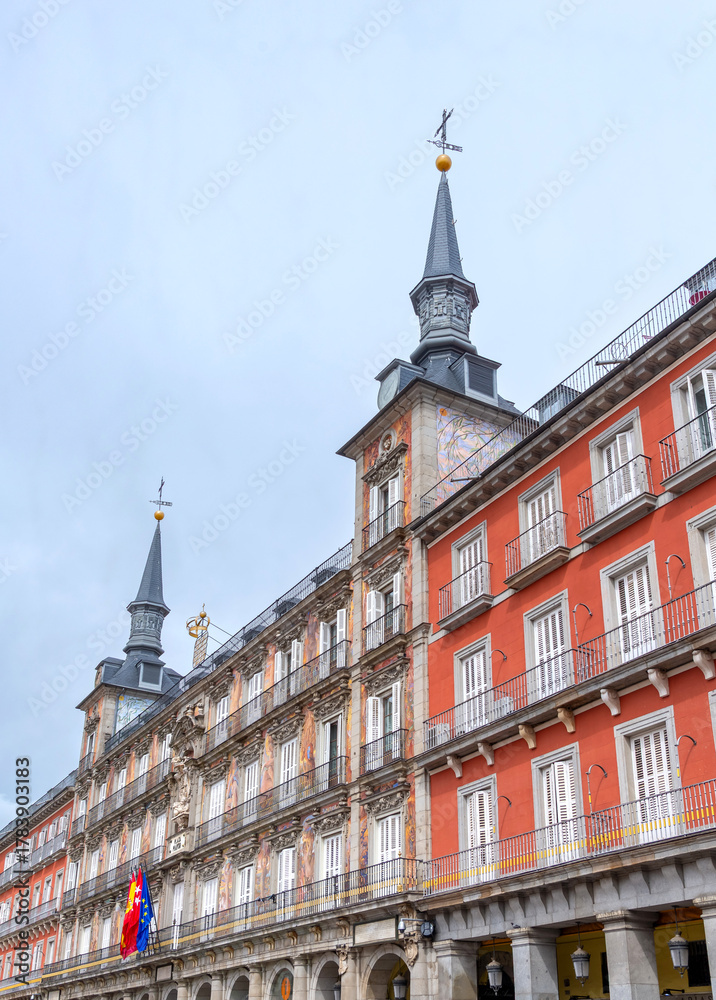 Obraz premium The highly decorated facade of Madrid's Casa de la Panadería on the Plaza Mayor, featuring vibrant frescoes, two ornate towers, multiple balconies, and flags flying