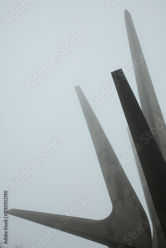Minimalist composition showing the pointed shapes of the Kosmaj Monument disappearing into thick fog