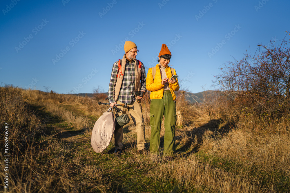 Obraz premium Couple hiking trail using smart phone for navigation