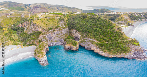 Fototapeta Naklejka Na Ścianę i Meble -  Aerial view of Arcomagno coast in Calabria Italy showing turquoise sea meeting rugged cliffs and hidden caves surrounded by lush Mediterranean vegetation symbolizing untouched natural beauty