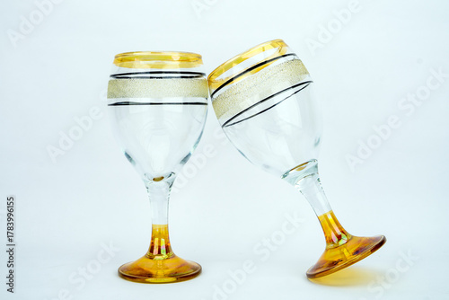 Pair of Vintage Gold and Glitter Banded Wine Glasses Clinking on White Background