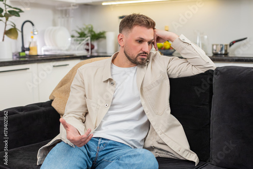 Картината върху платно Young man at home looks down and feels exhausted after rough day and low mood and heavy stress