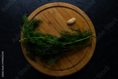 A photo of a kitchen board with herbs and garlic on it