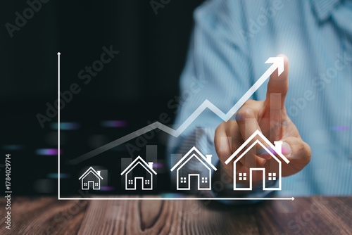Real estate growth concept. Businessman analyzing housing market trends and property investment with financial graph showing increasing home value and profit growth.