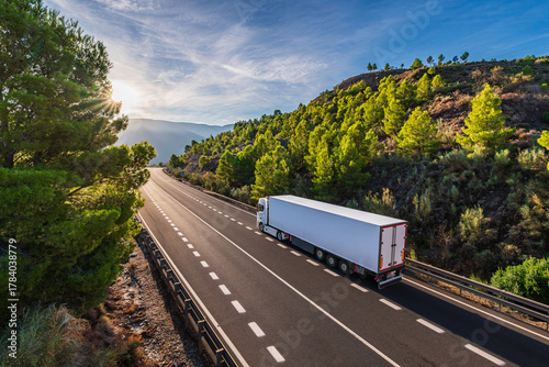 Refrigerated truck driving on a two-way road atop a mountain bordered by forest