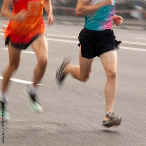 Two men in sportswear are running quickly along a city street