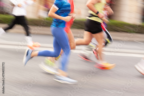 Several runners, men and women, jogging along a city street