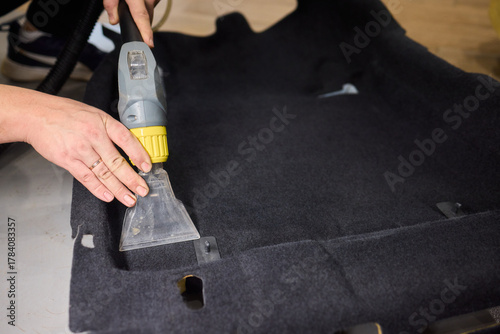 Automotive cleaning process, Professional vehicle upholstery maintenance and dirt removal, Detailed view of cleaning device removing grime from dark fabric upholstery