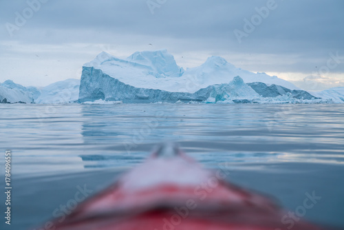 Giant icebergs floating in Ilulisat icefjord, Greenland. Massive icebergs, calved from the Sermeq Kujalleq Glacier, float through the Ilulissat Icefjord in western Greenland viewed from the kayak