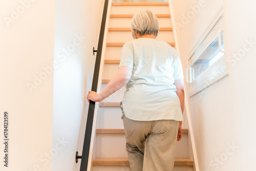 Fotografie Senior woman suffering from knee pain climbing stairs at home