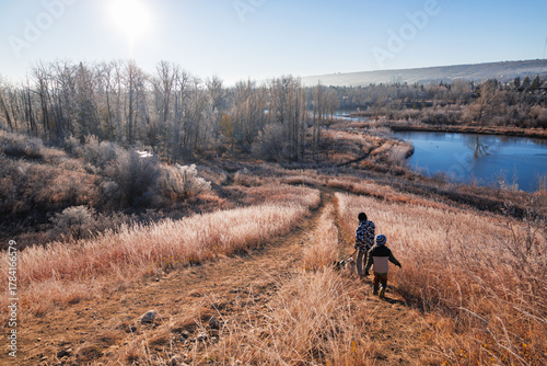 Two young boys walking down a hill with their dog in Bowmont Park, Calgary on a clear, wintry day
