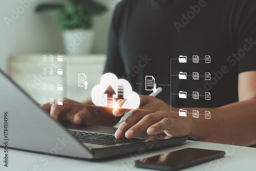 Businessman using laptop with digital cloud storage interface, data upload and file sharing system for online business. Concept of cloud computing, data management and technology innovation.
