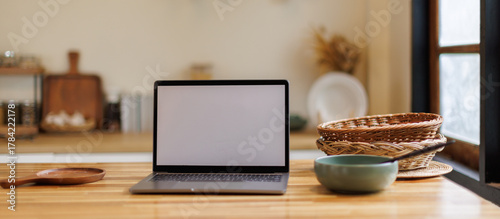 Open laptop with blank screen on a wooden desk in a kitchen room home office. Social media culinary concept, 
