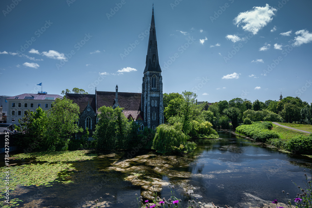 Fototapeta premium Anglican church of St. Alban’s stands peacefully beside a lake and trees in Copenhagen.
