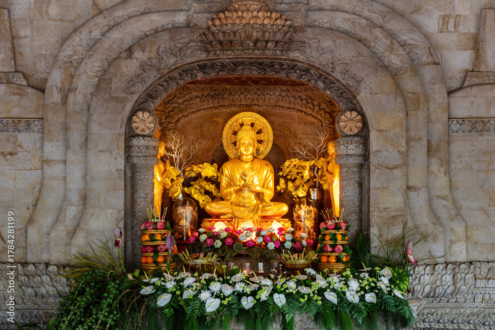 Fototapeta premium Interior scene of the Buddhist temple of dharma giri vihara in Northern Bali, Indonesia, showing golden sculpture depicting Buddha. 