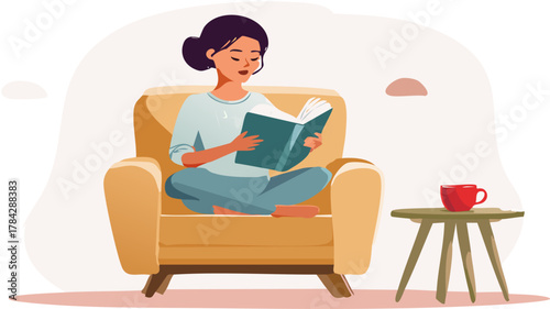 A young woman relaxing and reading a book while sitting cross-legged in a comfortable armchair.