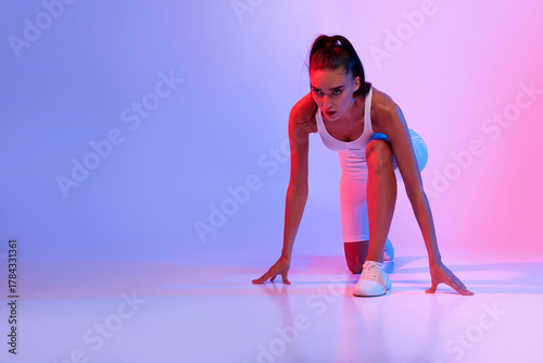 Fényképezés An athletic female is positioned in a crouch start, ready to race