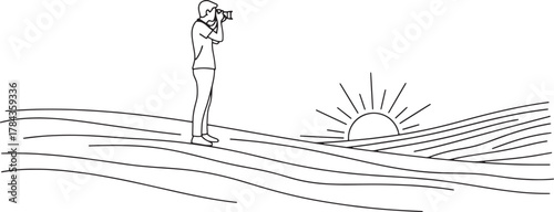 Person with binoculars observing a sunrise over wavy landscape