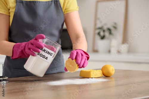 Bild auf Leinwand Young woman with lemon and baking soda cleaning table in kitchen, closeup