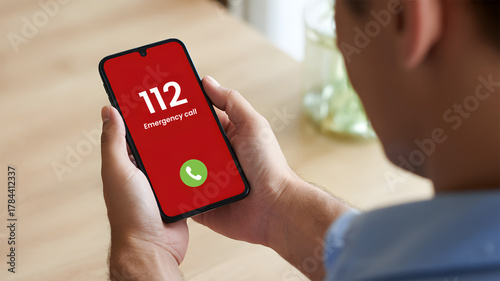 Man holding smartphone with 112 European emergency call number on red screen