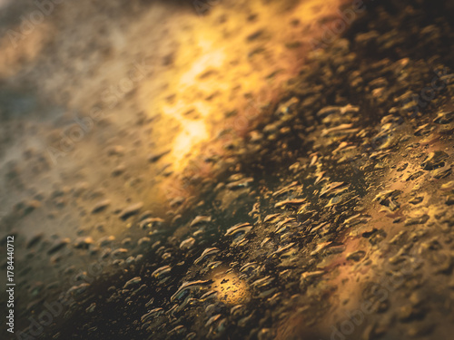 Close-up view of raindrops on a car window during a rainy day. Water droplets create a soft abstract pattern with reflections and blurred lights outside. Perfect for backgrounds, weather concepts