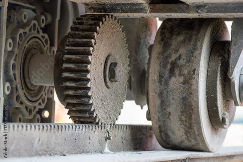 Close-up view of a complex gear system in an industrial machine, demonstrating wear and dust accumulation