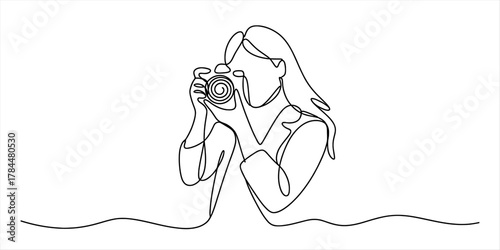 Minimalist continuous line drawing of a woman holding a camera, capturing life's moments, symbolizing artistic expression and a photography hobby.