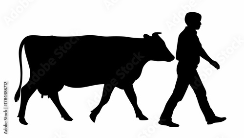 Silhouette of a cow walking alongside a silhouette of a person walking in the same direction outdoors