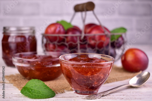 Homemade plum jam in a glass bowl against the background of fresh plums.
