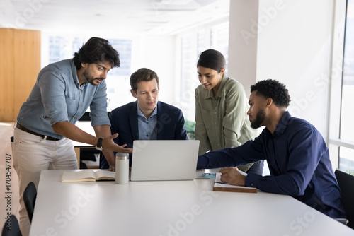 Focused polyethnic businesspeople engaged in brainstorm looking at notebook screen