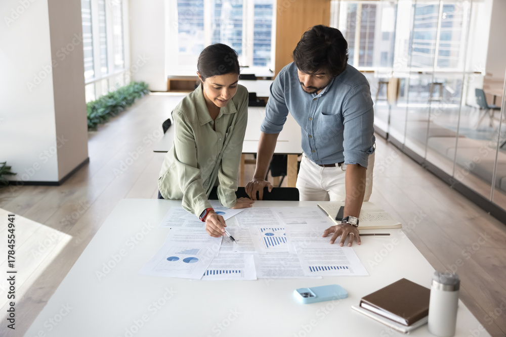 Fototapeta premium Young female mentor share knowledge discuss statistics with male trainee