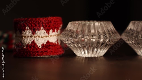 Knitted Christmas heart decoration paced on wooden table, being removed from the frame by a hand.
