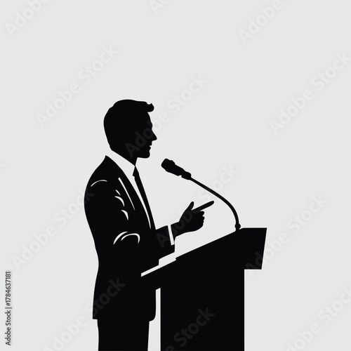 Silhouette of a man in a suit speaking at a podium with a microphone.