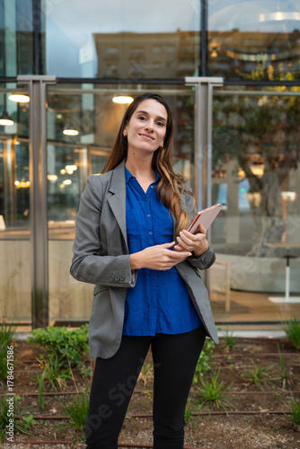 Confident businesswoman holding tablet outdoors in modern setting