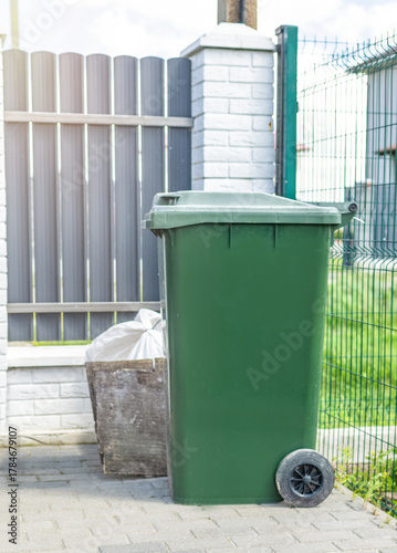 waste collection station in tidy yard, neighborhood waste area with wellmaintained lawn and bins, clean and organized curbside waste disposal area in residential neighborhood with sunlight