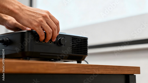Hands adjusting a video projector on a wooden surface, preparing for a presentation or movie night