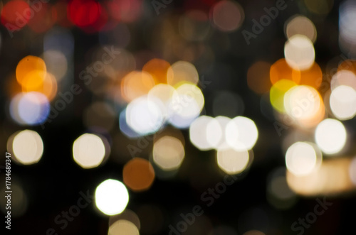 A blurred city street image at night. Abstract blur urban city street road with lighting bokeh for background. There is noise in the photo due to lack of light.
