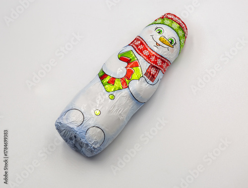 Chocolate snowman wrapped in festive foil packaging closeup on white.
