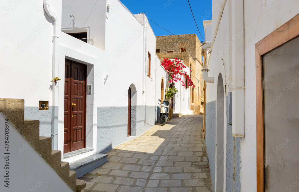 Fototapeta premium Cobblestone street with white houses on Rhodes island. Lindos village, Dodecanese, Greece.