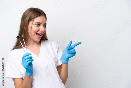 Dentist woman holding tools isolated on white background pointing finger to the side and presenting a product