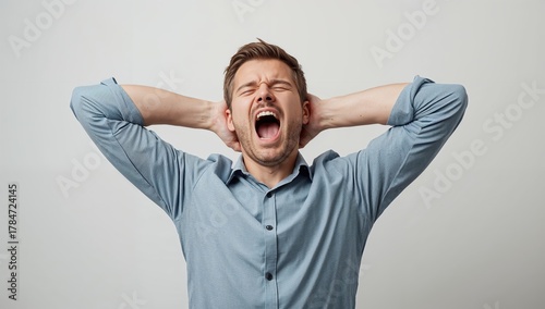 Frustrated man with hands on head screaming in exasperation, conveying stress and overwhelming pressure
