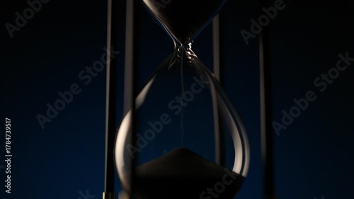 macro shot of sand flowing inside a transparent hourglass, illustrating balance, decay, and the eternal rhythm of time