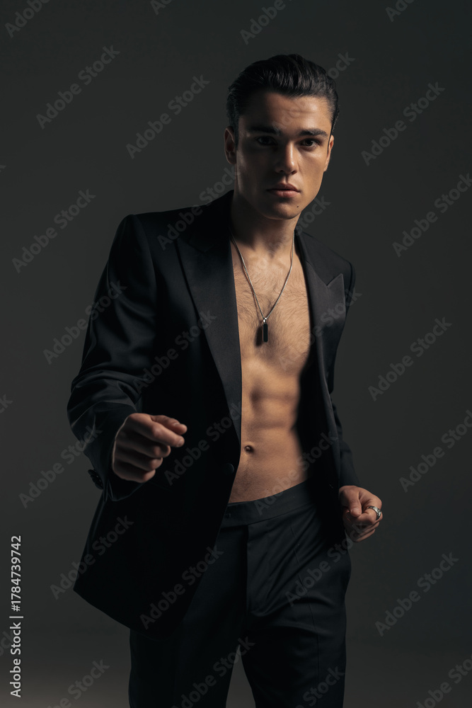 Obraz premium sexy young man in tuxedo with no shirt looking forward and posing