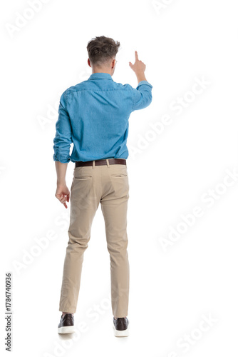 Back view of casual man standing and pointing up