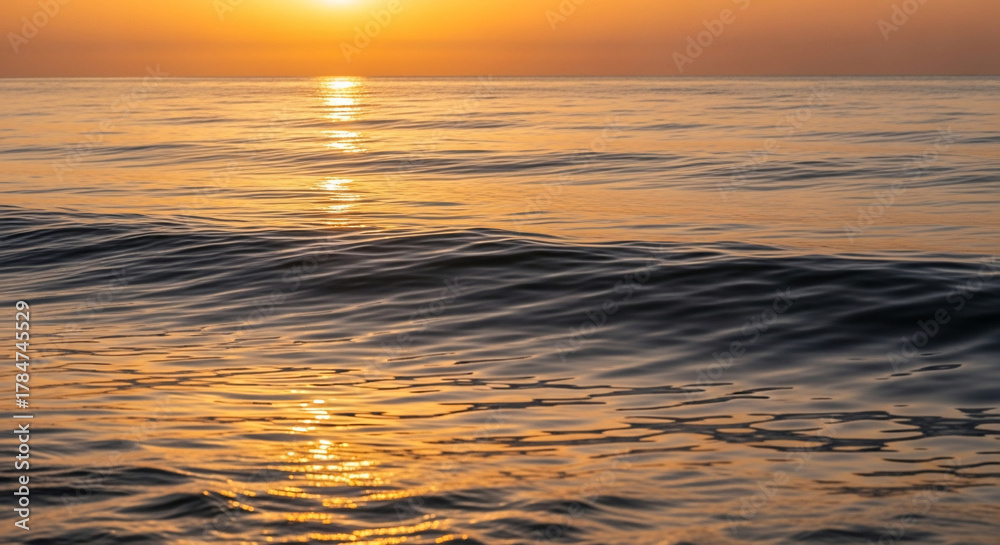 Obraz premium Golden hour bathes the tranquil ocean waves in a warm, serene light