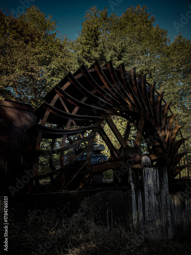 Rusty old water wheel (watermill) surrounded by green trees